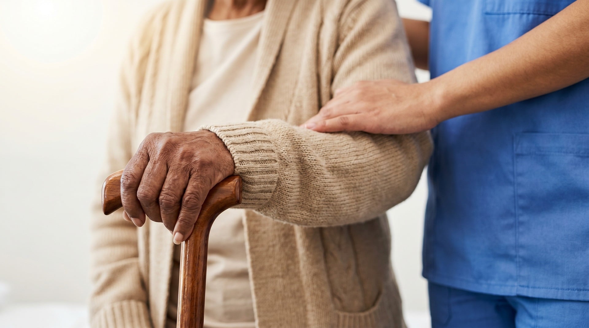 Aidant familial soutenant une personne âgée avec une canne à domicile